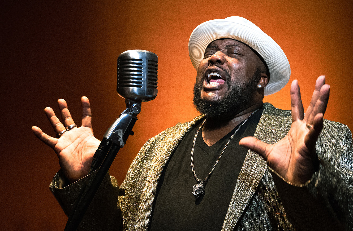 Sugaray singing into standing microphone.
